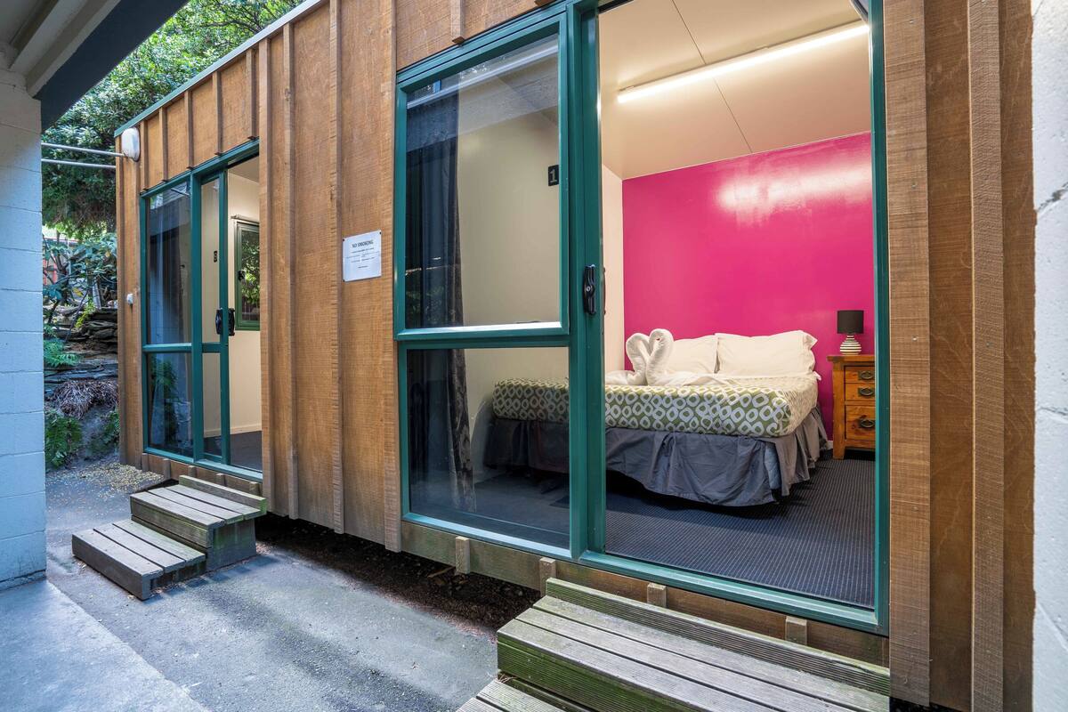 A modern room with a bed, a nightstand, and a window.