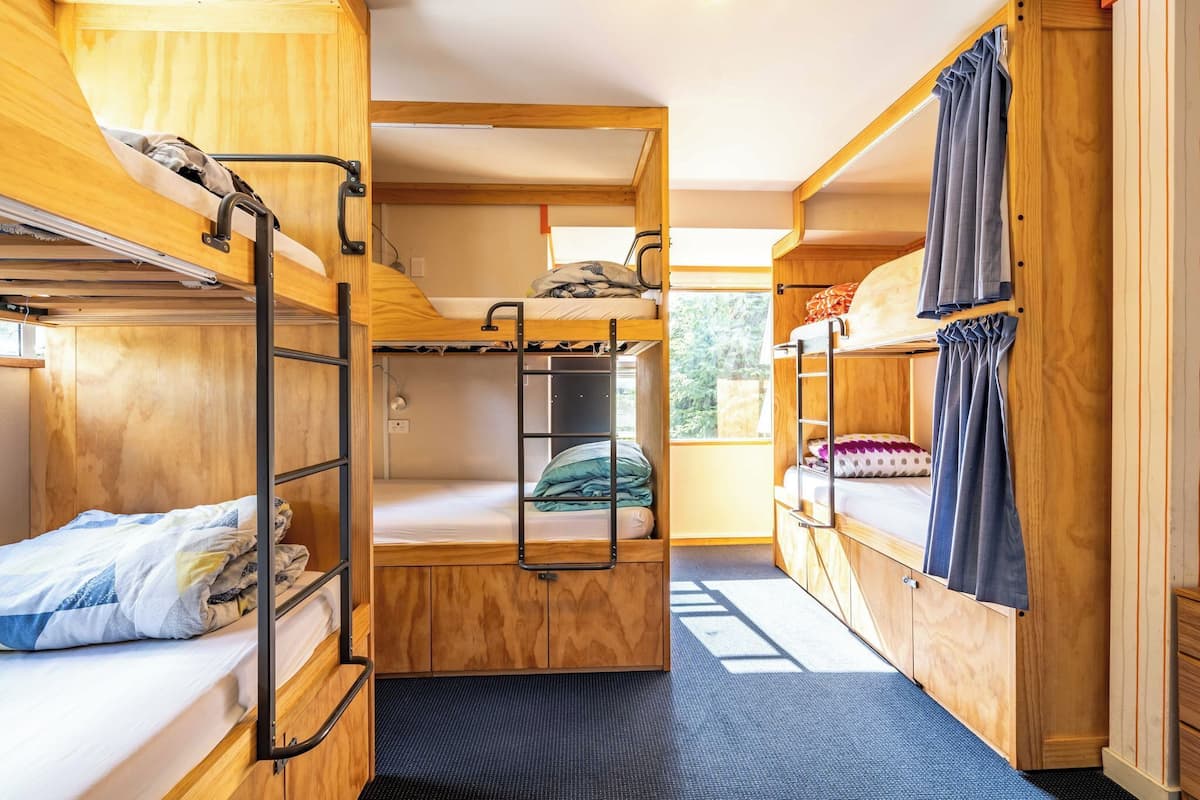 A compact, wooden interior with bunk beds, a small kitchenette, and a window providing natural light.