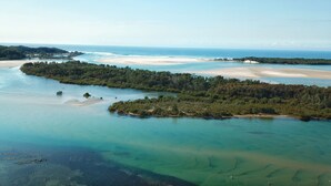 Vista aérea de una zona costera con aguas cristalinas, playas de arena y abundante vegetación.