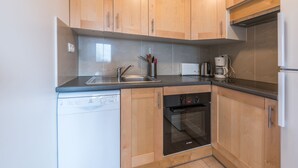 Una cocina compacta con armarios de madera, lavavajillas, horno y cafetera.