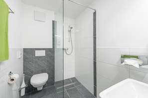 Un baño moderno con cabina de ducha de vidrio, inodoro y lavamanos.