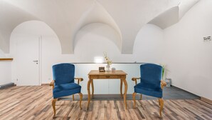 A room with a wooden table, two blue chairs, and a vase with flowers. - Hotel City Rooms Wels (Wels)