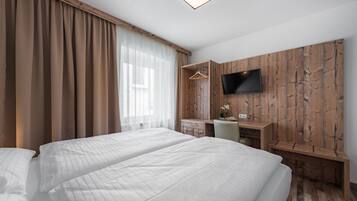 Une chambre d’hôtel avec deux lits, un bureau, une chaise, une télévision et un mur recouvert de panneaux en bois.
