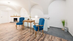 A spacious room with a wooden floor, a fireplace, a dining table with chairs, and a potted plant. - Hotel City Rooms Wels (Wels)