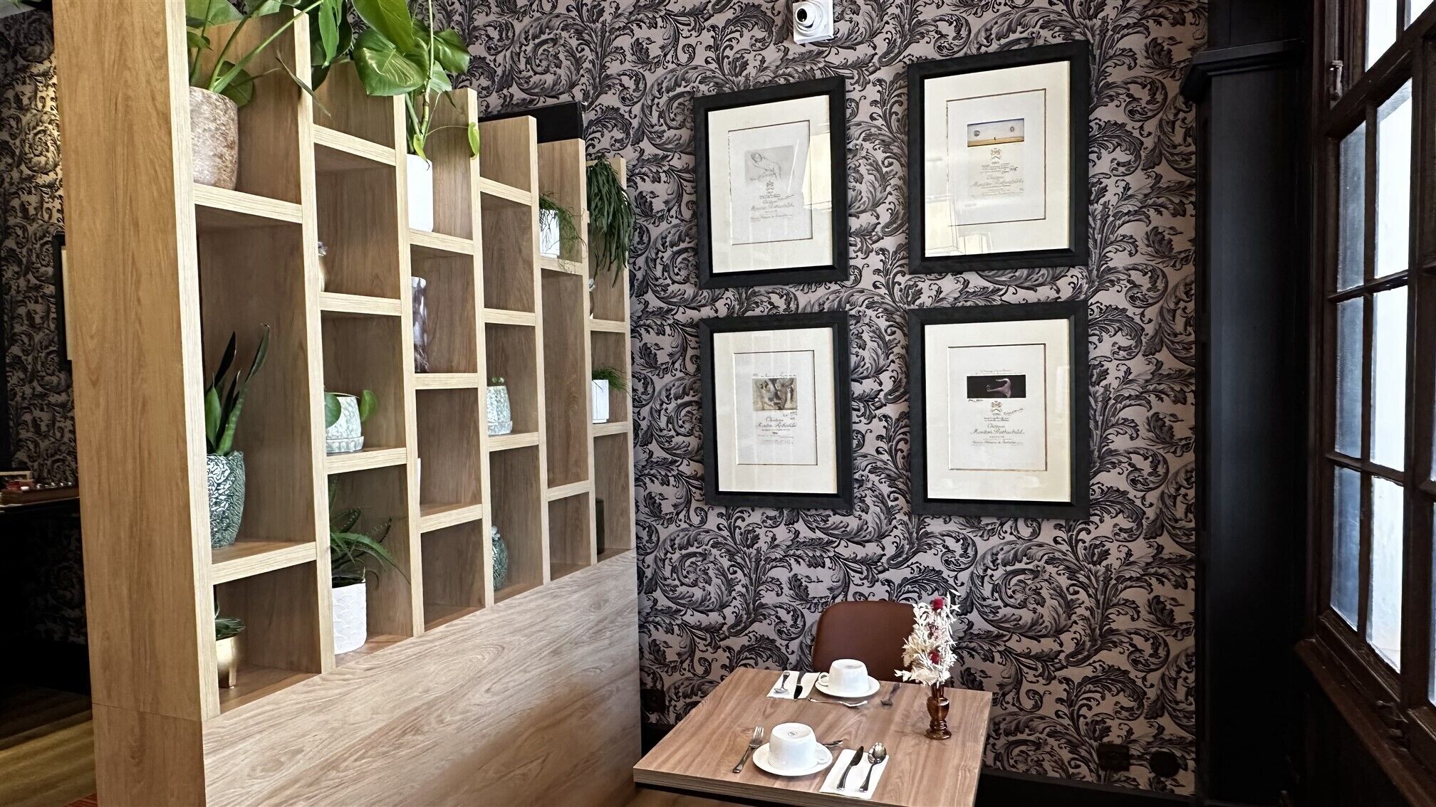 A hallway with a wooden partition, framed certificates on the wall, and a table with a teapot and cups.