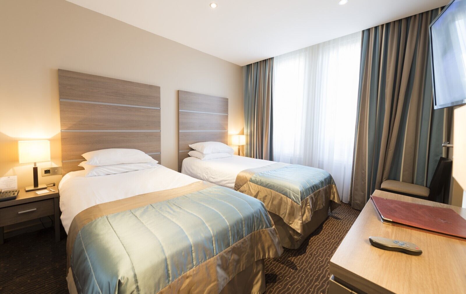Una habitación de hotel con dos camas, un escritorio, una silla y un televisor.