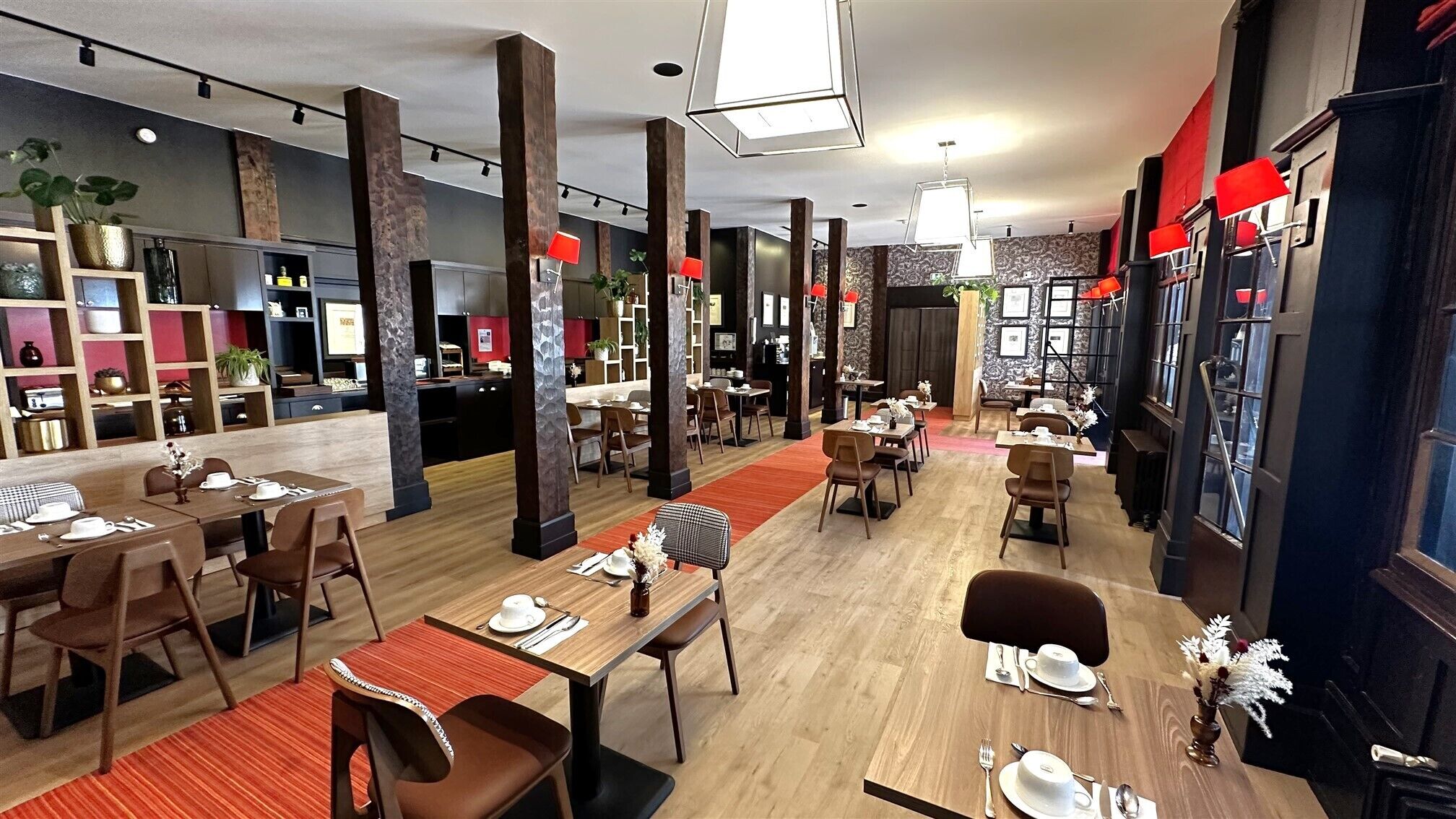 A modern restaurant with multiple dining areas, wooden tables, and chairs.