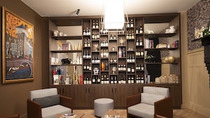 Une pièce chaleureuse avec une vaste collection de vins, des fauteuils confortables et une cheminée.