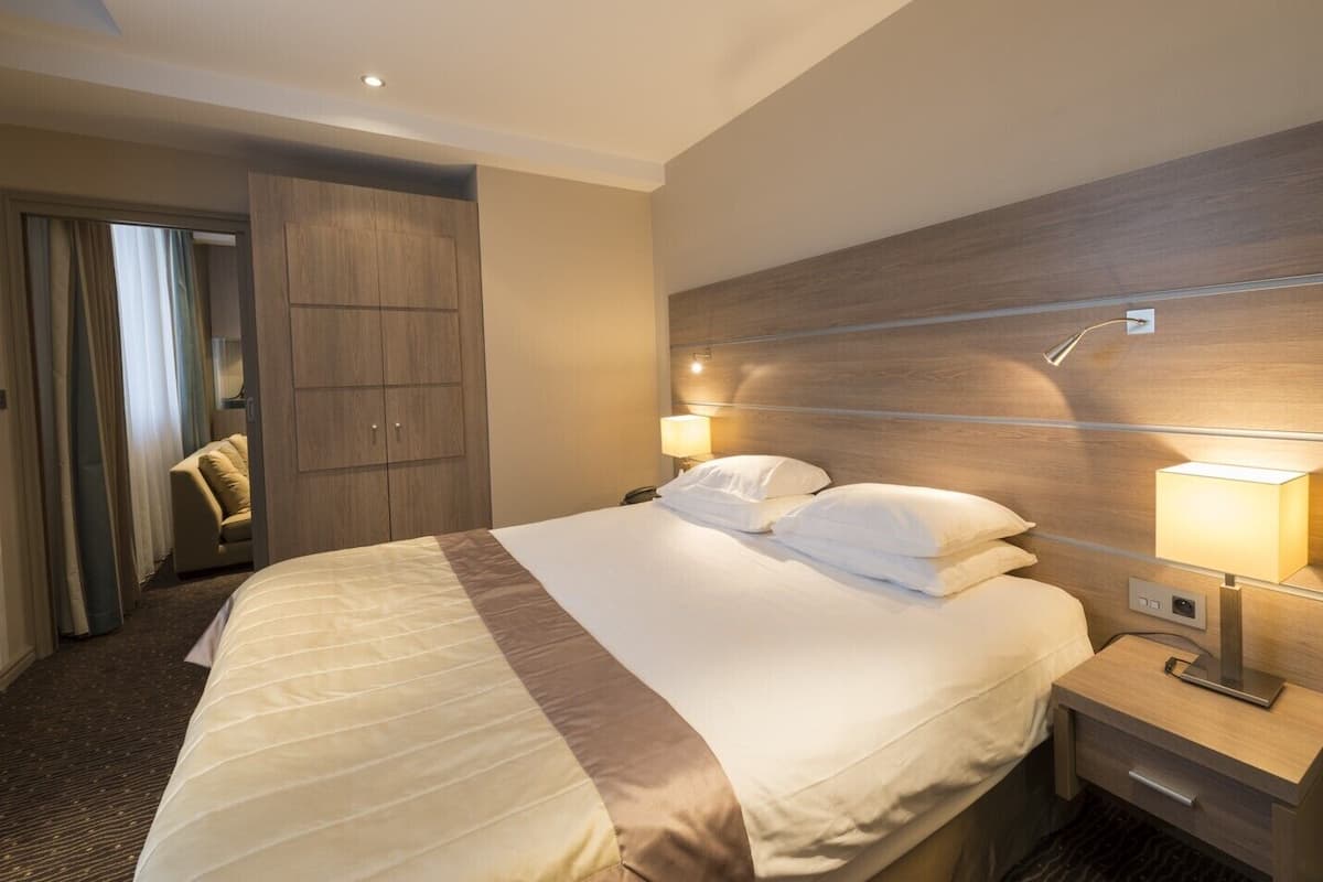Une chambre d’hôtel avec un grand lit, des lampes de chevet, une armoire et une porte donnant sur une salle de bain.
