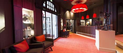 Un vestíbulo de hotel con mostrador de recepción, zona de estar y amplias ventanas.
