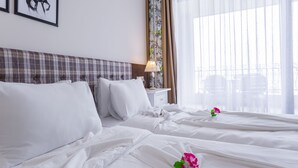 Une chambre d’hôtel avec un lit, une table de chevet, une lampe et une fenêtre avec des rideaux.