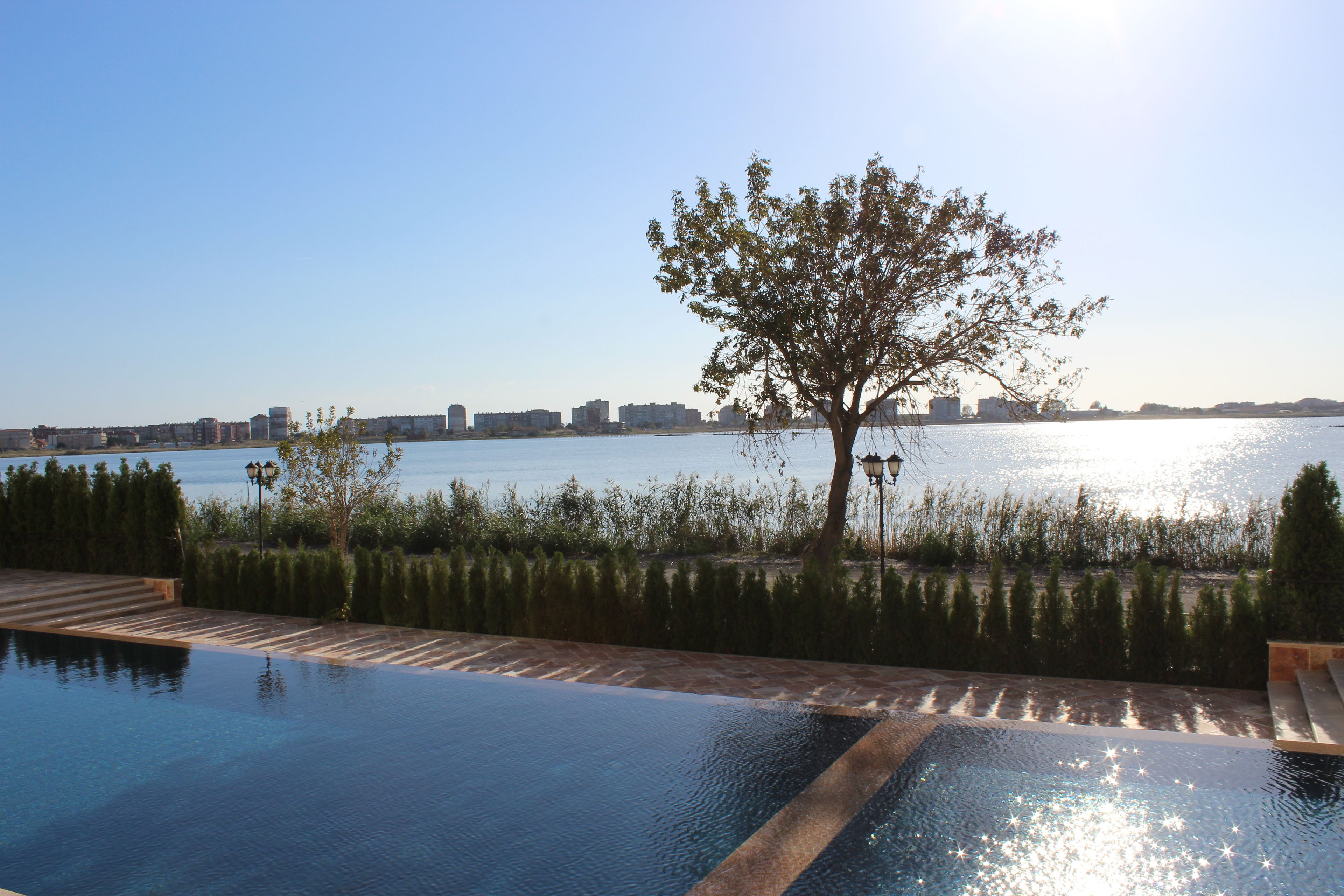 A swimming pool with a view of a body of water and a cityscape in the background.