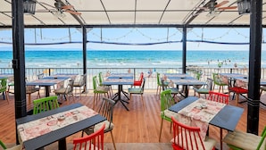 Un espace extérieur aménagé avec des tables et des chaises, donnant sur une plage.