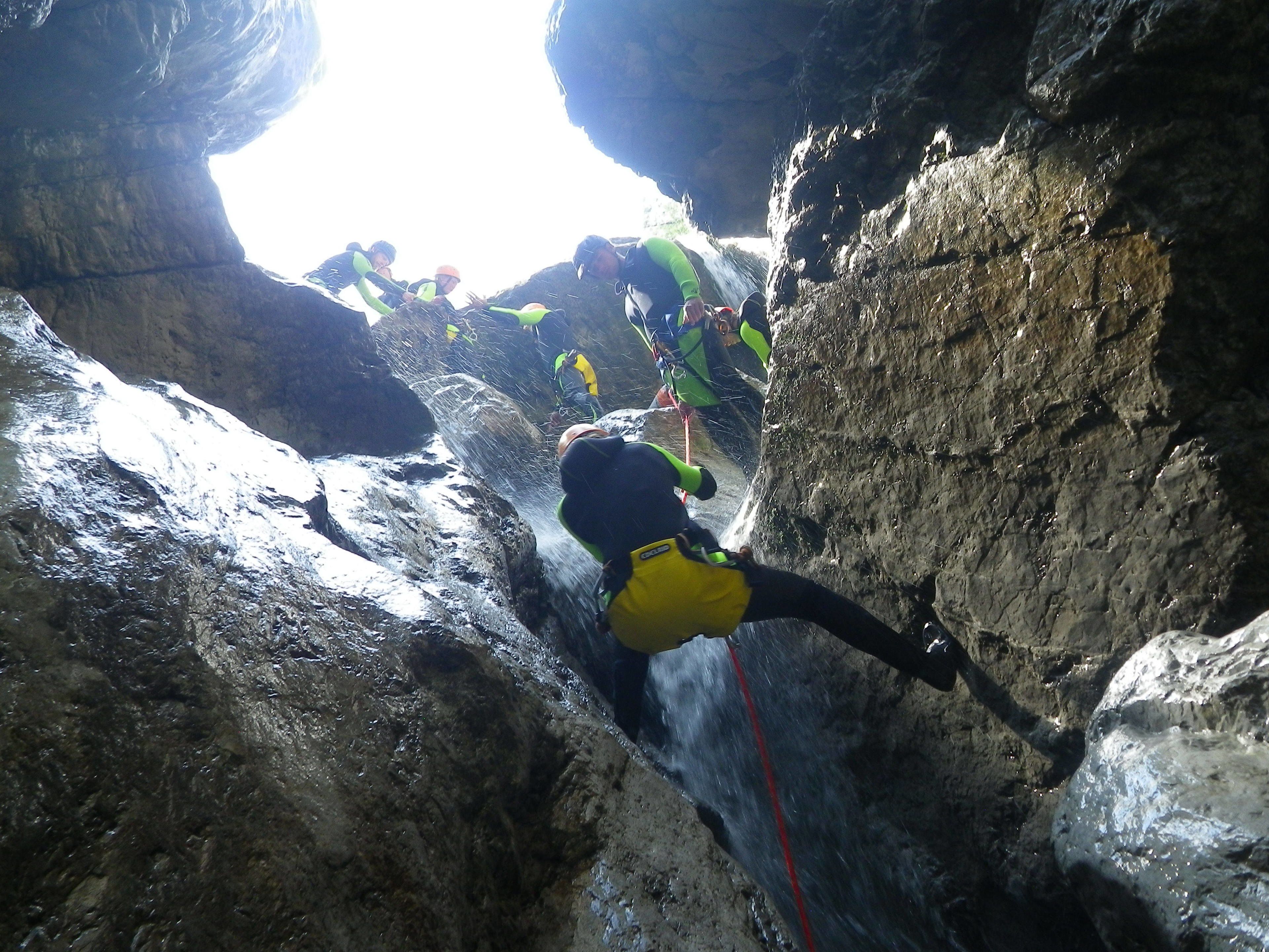 Una estrecha vía de escalada en roca con cuerda y escaladores con arneses.