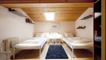 Una habitación con dos camas, un radiador, una ventana y una alfombra negra.
