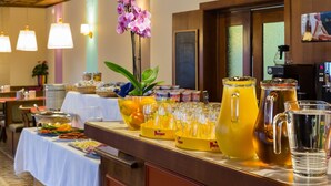 Een buffetopstelling met diverse etenswaren, een karaf met geel drankje en een karaf met water.