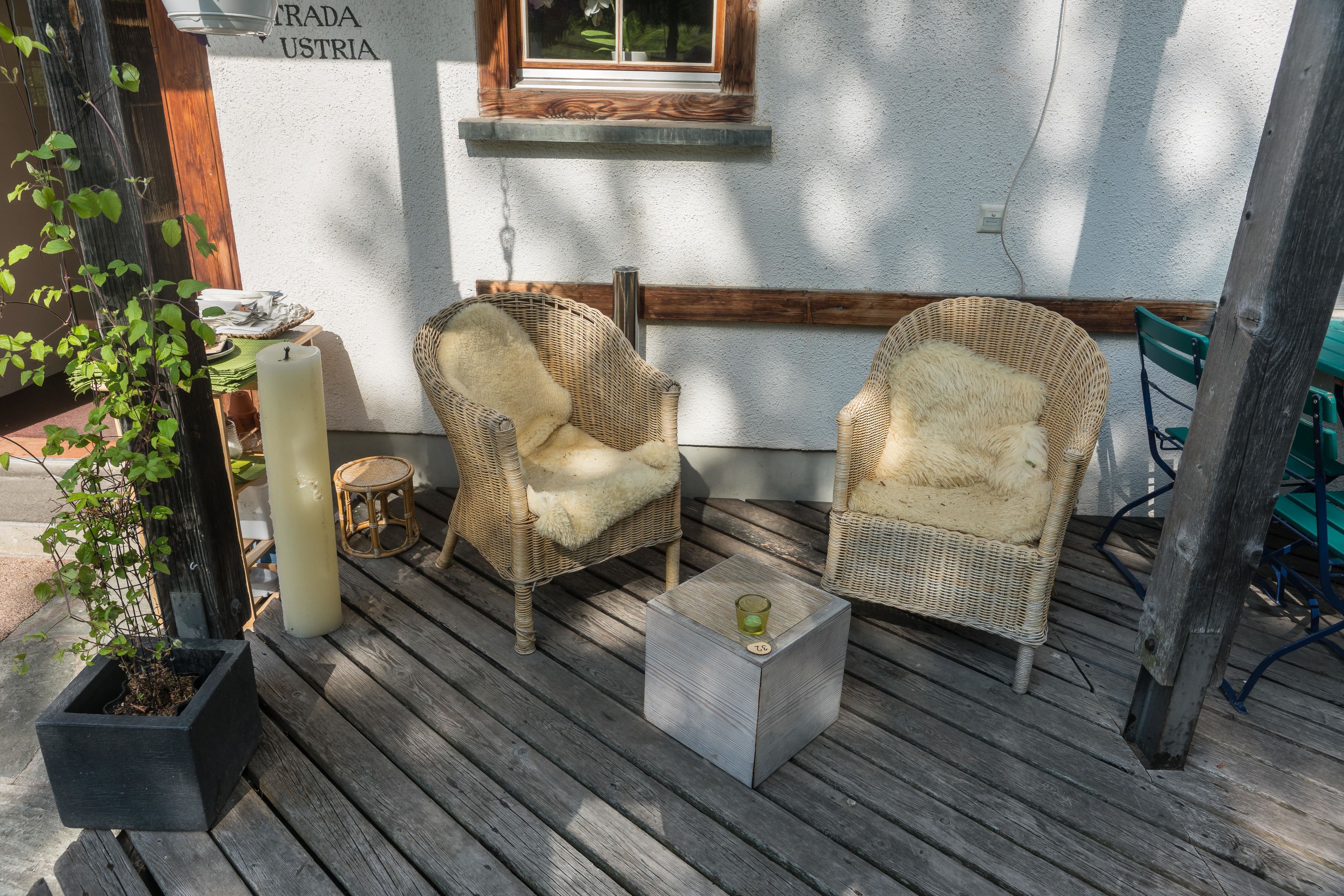 Une terrasse en bois avec des chaises en osier et une petite table.