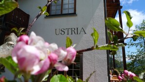 Ein Gebäude mit der Aufschrift "USTRIA" an der Fassade, umgeben von Grünpflanzen und Blumen.