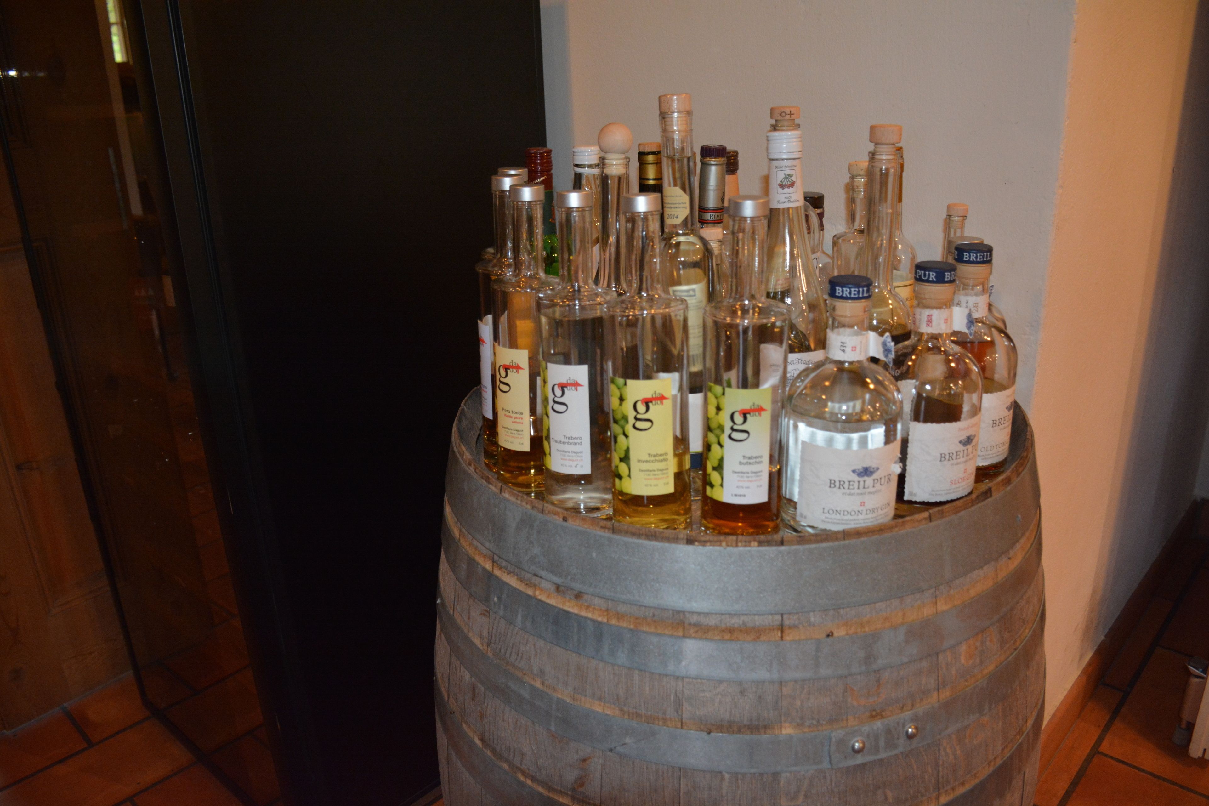 A wooden barrel filled with various bottles of alcohol, including brands like 'Breil' and 'G&G'.