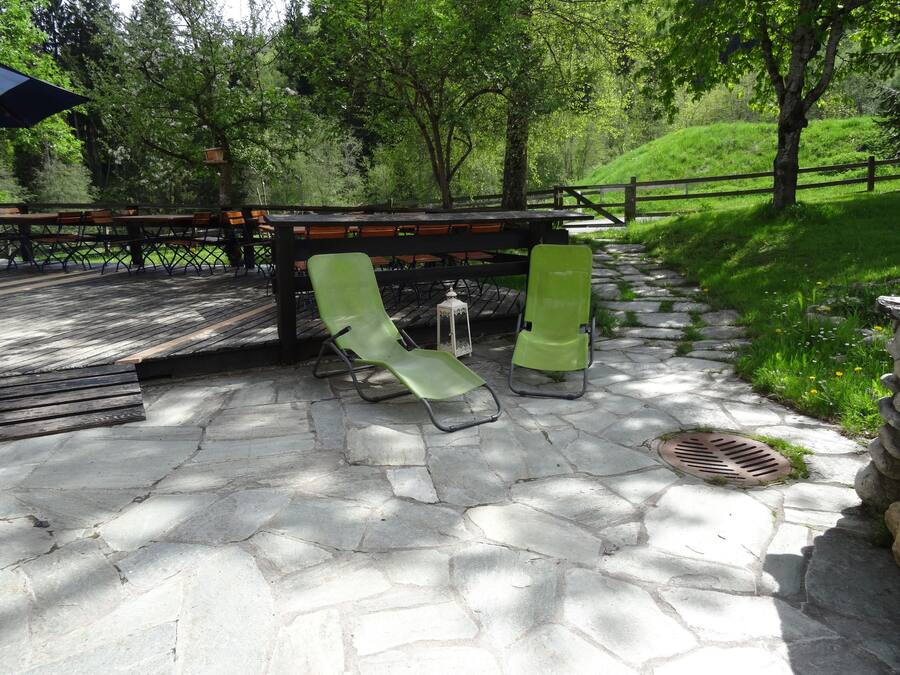 Un patio de piedra con dos sillones verdes y una mesa de madera.