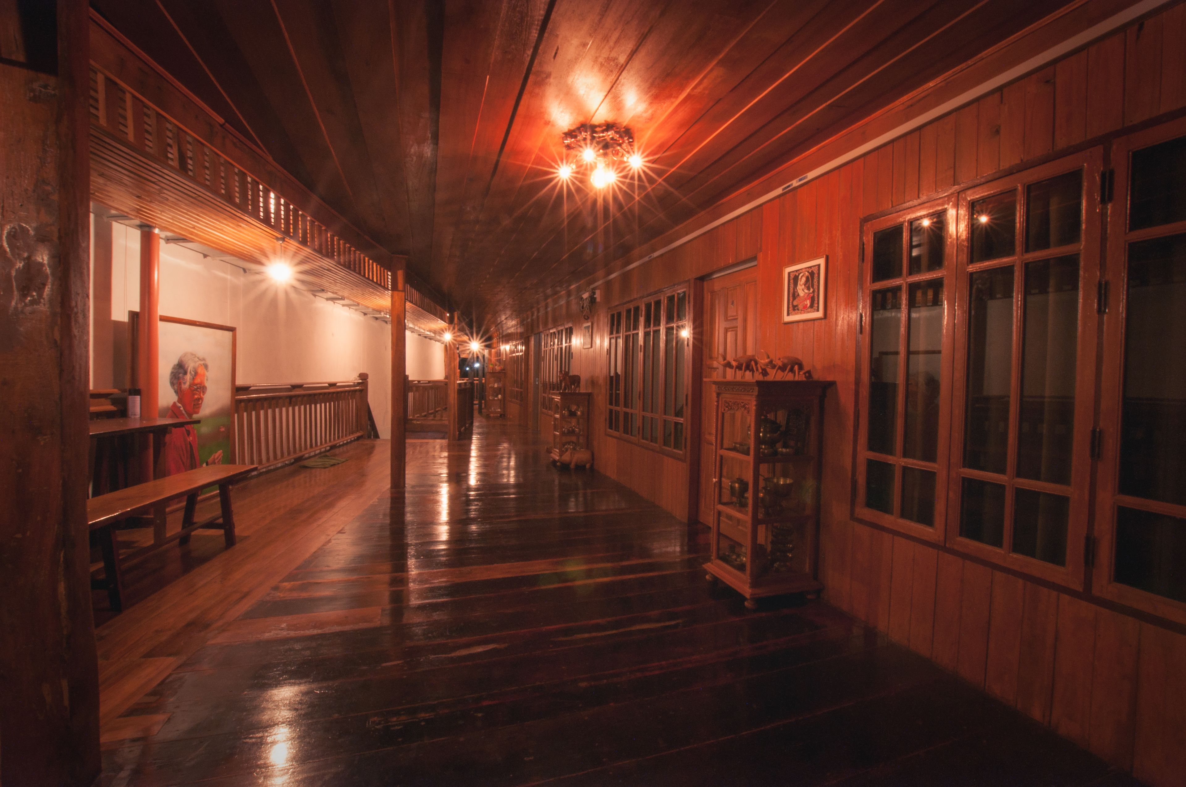A long, narrow hallway with wooden walls and floors, benches along one side, and a display cabinet on the other.