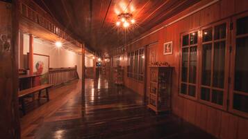 A long, narrow hallway with wooden walls and floors, benches along one side, and a display cabinet on the other.