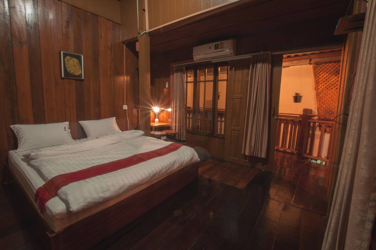 Une chambre à coucher aux murs lambrissés, avec un lit, une table de chevet et une fenêtre avec des rideaux.