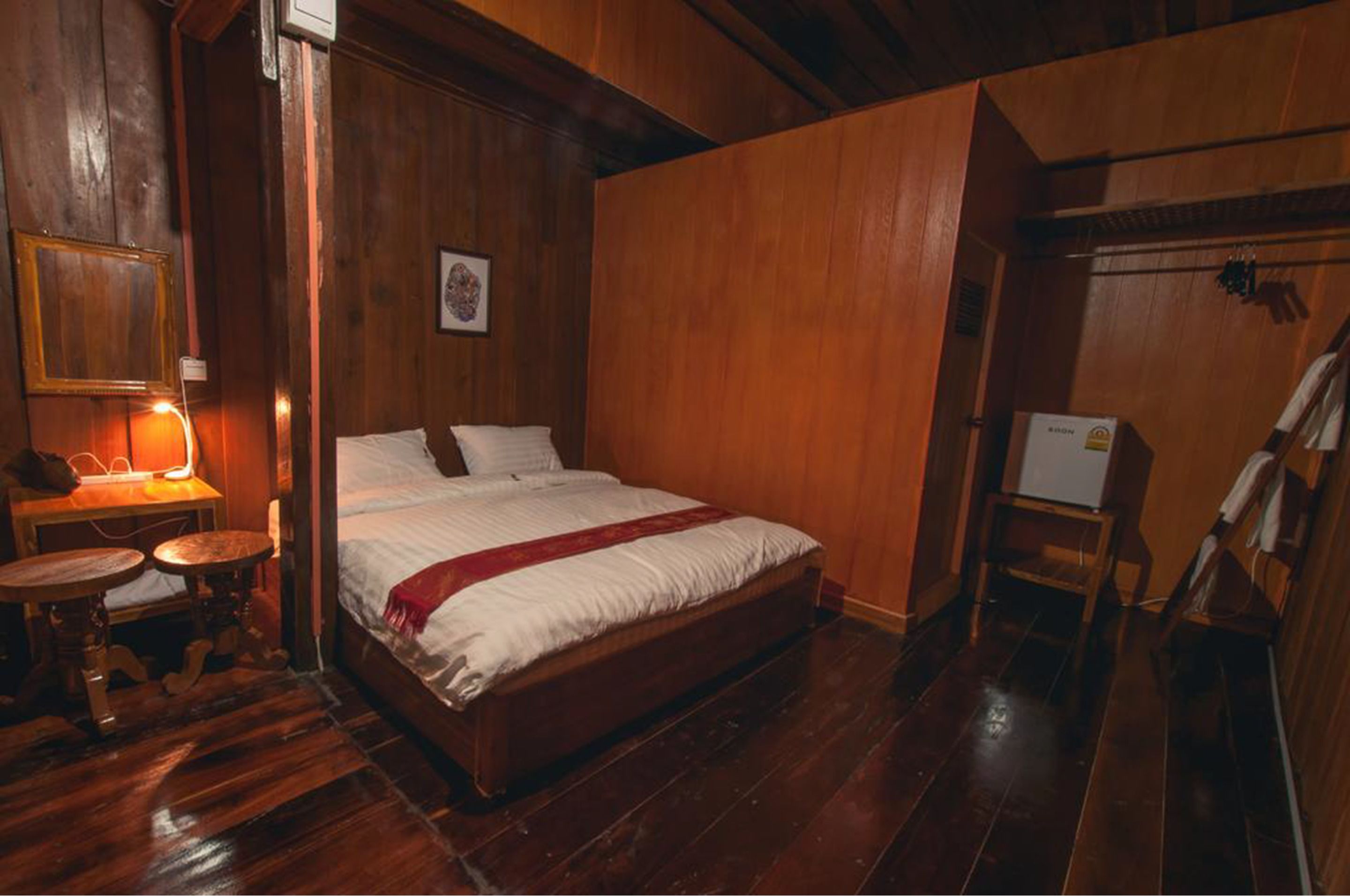 Una habitación de madera con una cama, una mesita y una silla.