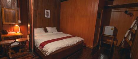 Una habitación de madera con una cama, una mesita y una silla.