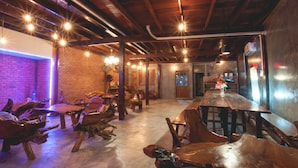 A rustic interior with exposed wooden beams, a long wooden bar, and unique wooden chairs. - The History Cafe' & Guesthouse (Sukhothai)