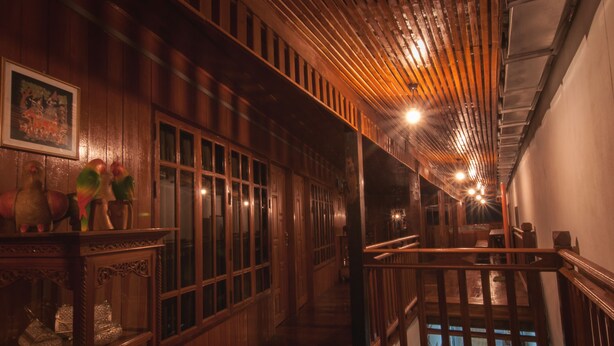 A wooden interior with a staircase, wooden railings, and a framed picture on the wall. - The History Cafe' & Guesthouse (Sukhothai)