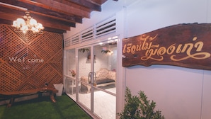 A reception area with a wooden bench, a 'Welcome' sign, and a 'Grooming' sign on the wall. - The History Cafe' & Guesthouse (Sukhothai)