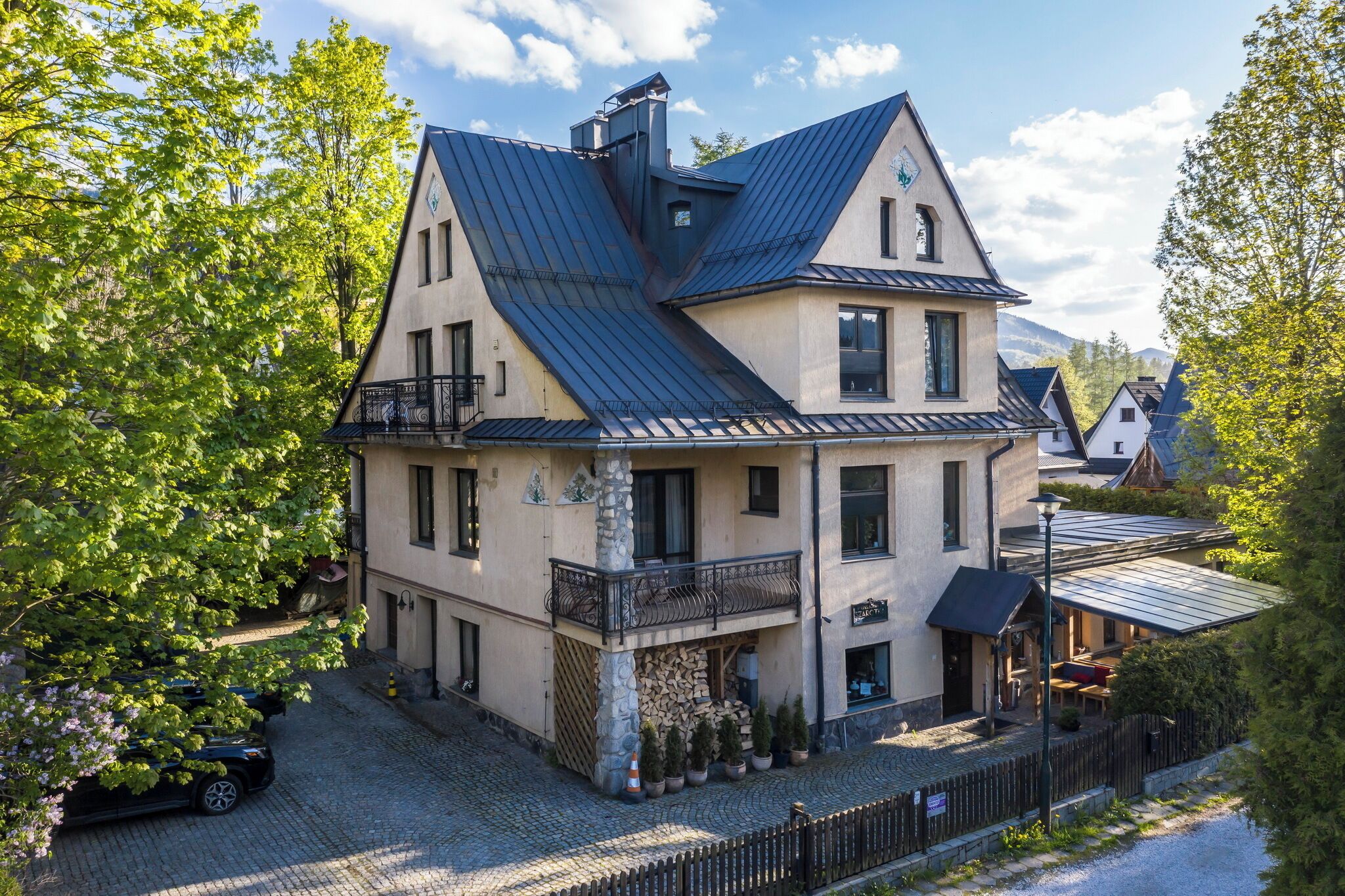 A two-story building with a sloped roof, a balcony, and a stone base.