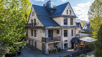 A two-story building with a sloped roof, a balcony, and a stone base.