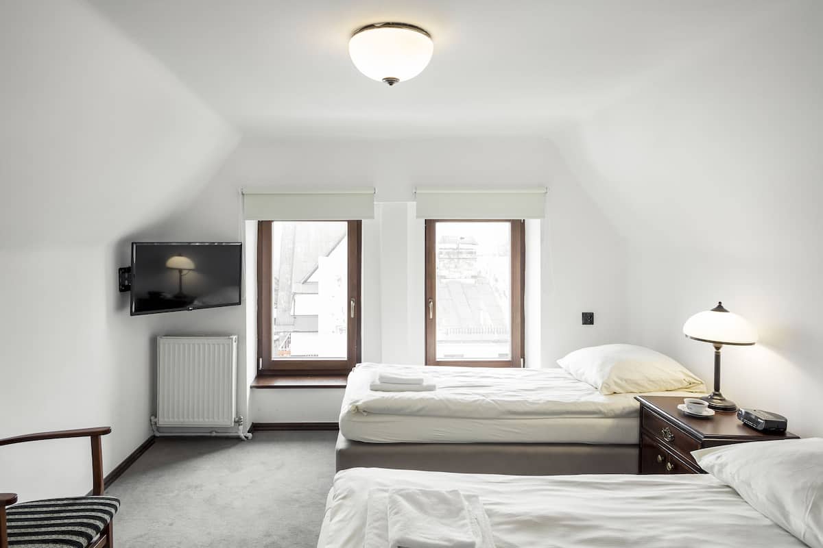 Una habitación de hotel con una cama, una silla, un televisor y un ventanal.