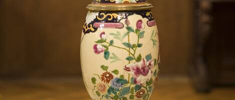 A table lamp with a floral design on the base, placed on a patterned tablecloth.