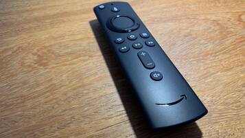 A black remote control on a wooden surface.