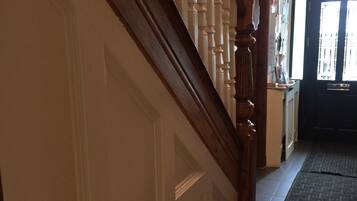A wooden staircase with white balusters leading to a door with a white panel design.
