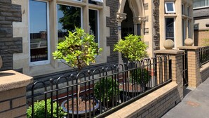 A building with multiple windows, stone and brick facade, and a black metal fence. - The Riverhouse (Cardiff)