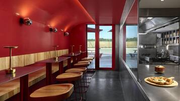 A modern bar area with red walls and wooden bar stools.