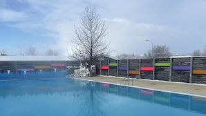 Une piscine à l’eau d’un bleu limpide, entourée d’une clôture en bois ornée de rayures horizontales colorées.