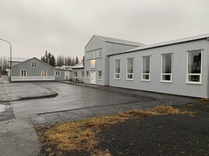 A building with a flat roof, multiple windows, and a paved area with a picnic table.
