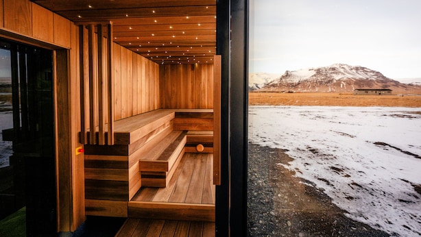 A wooden interior with a view of a snowy landscape and a mountain. - UMI Hotel (Rangárþing eystra)