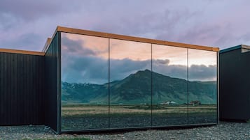 Un bâtiment moderne doté d’une grande façade vitrée qui reflète un paysage montagneux.