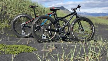 Dos bicicletas estacionadas sobre una superficie pavimentada con césped y un paisaje montañoso al fondo.