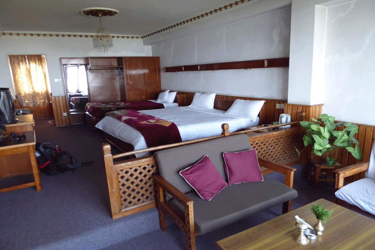 A hotel room with two beds, a sofa, a table, and a TV.