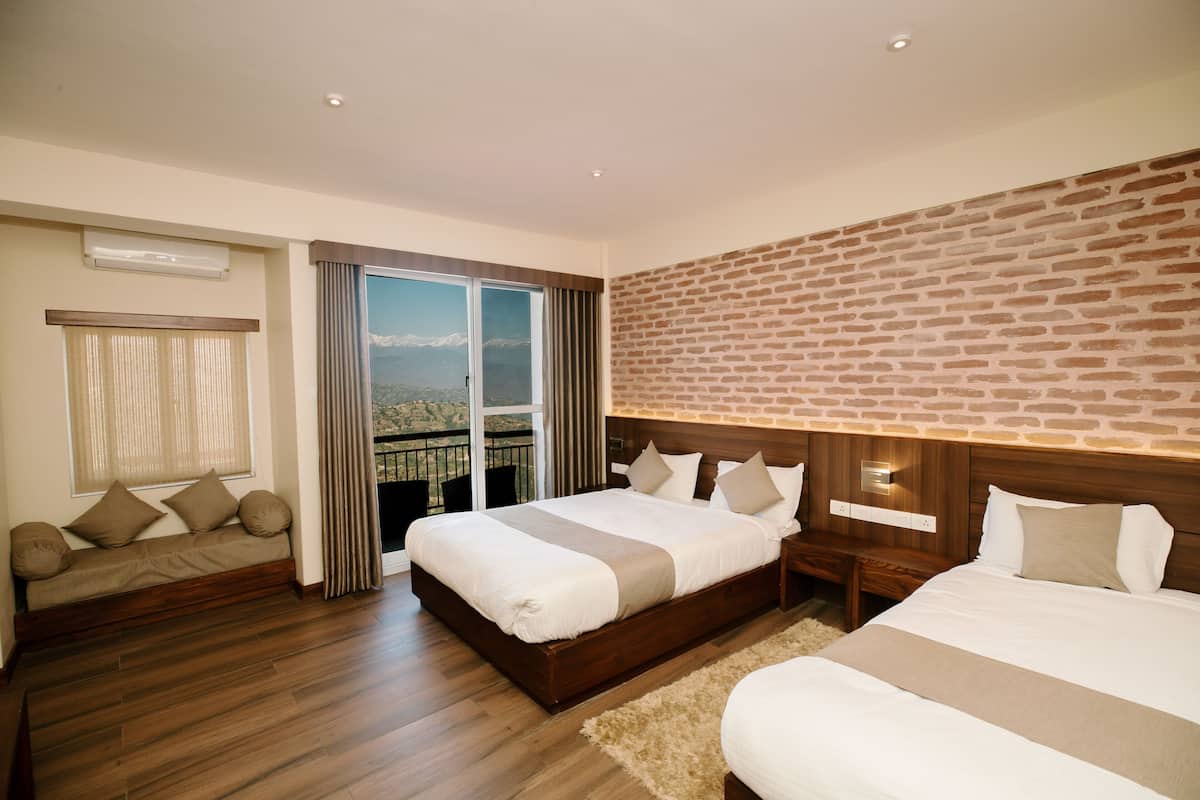 A hotel room with a large bed, a sofa, a view through a sliding door, and a brick wall.