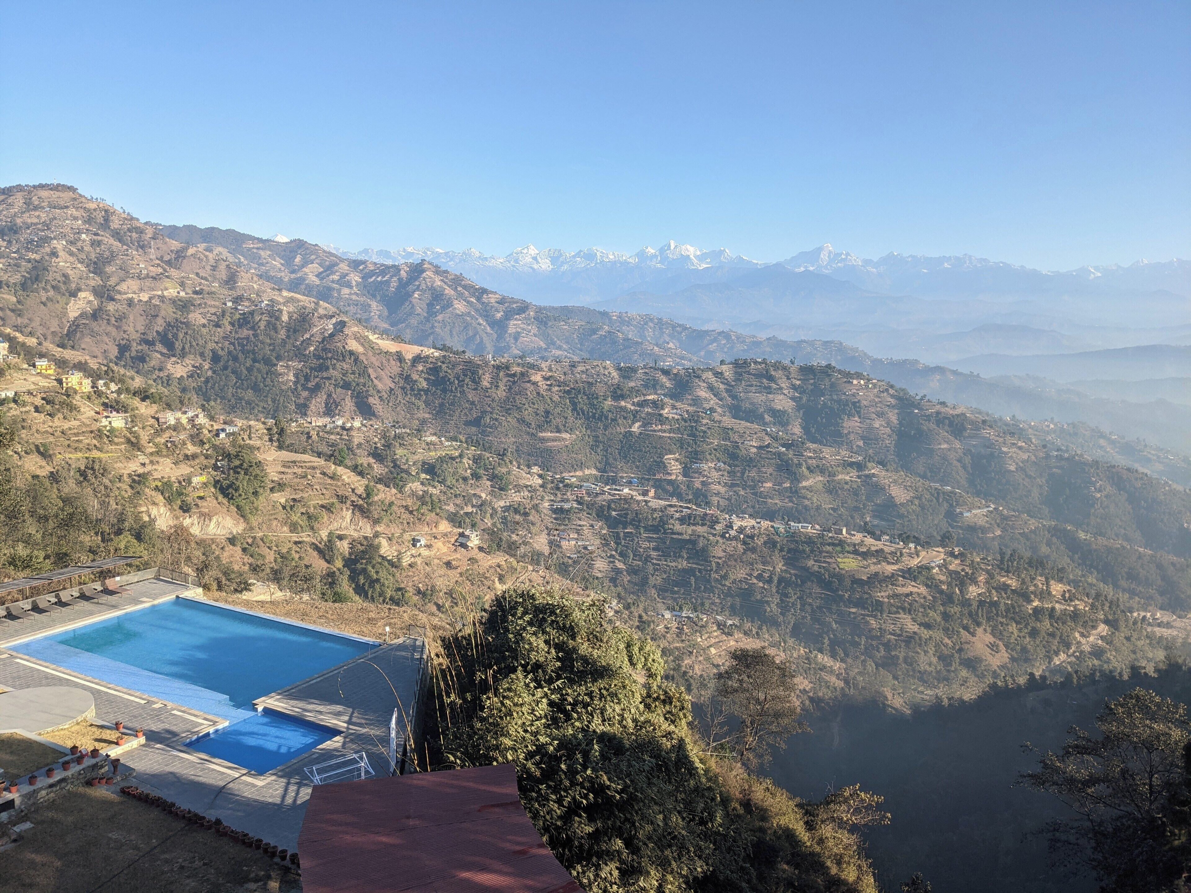 A mountainous landscape with a swimming pool and a view of distant snow-capped mountains.