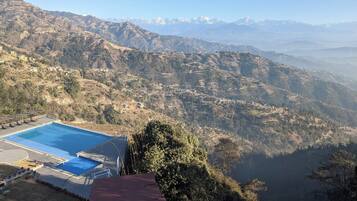 A mountainous landscape with a swimming pool and a view of distant snow-capped mountains.