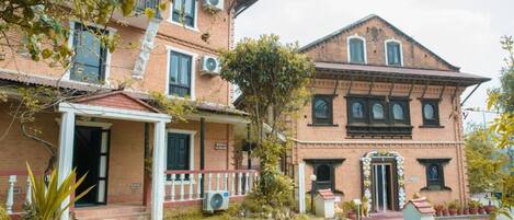Een tweelaags bakstenen gebouw met een veranda en een kleine tuin.